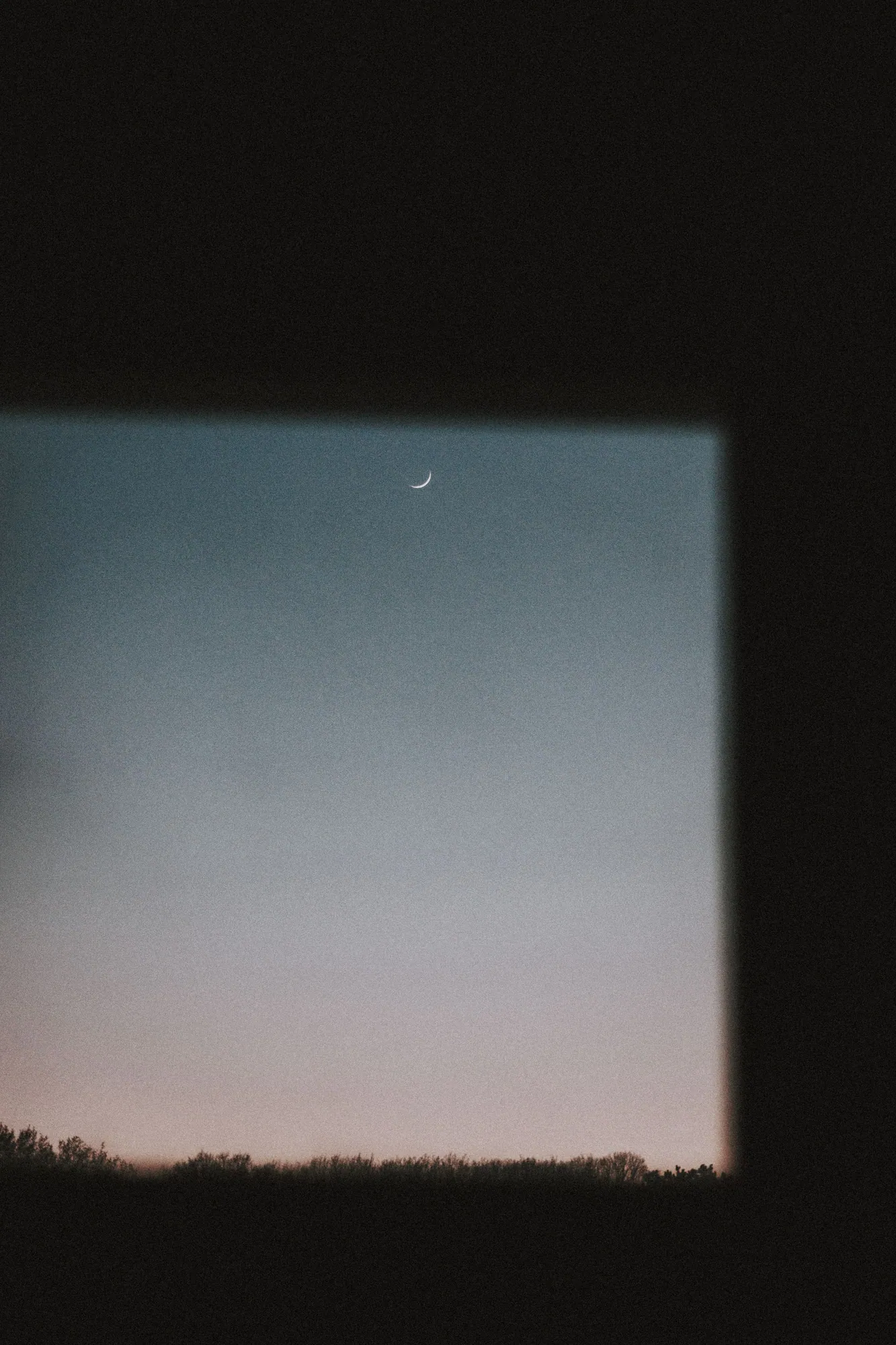 Luna creciente sobre una pared clara, en un cielo nocturno despejado.