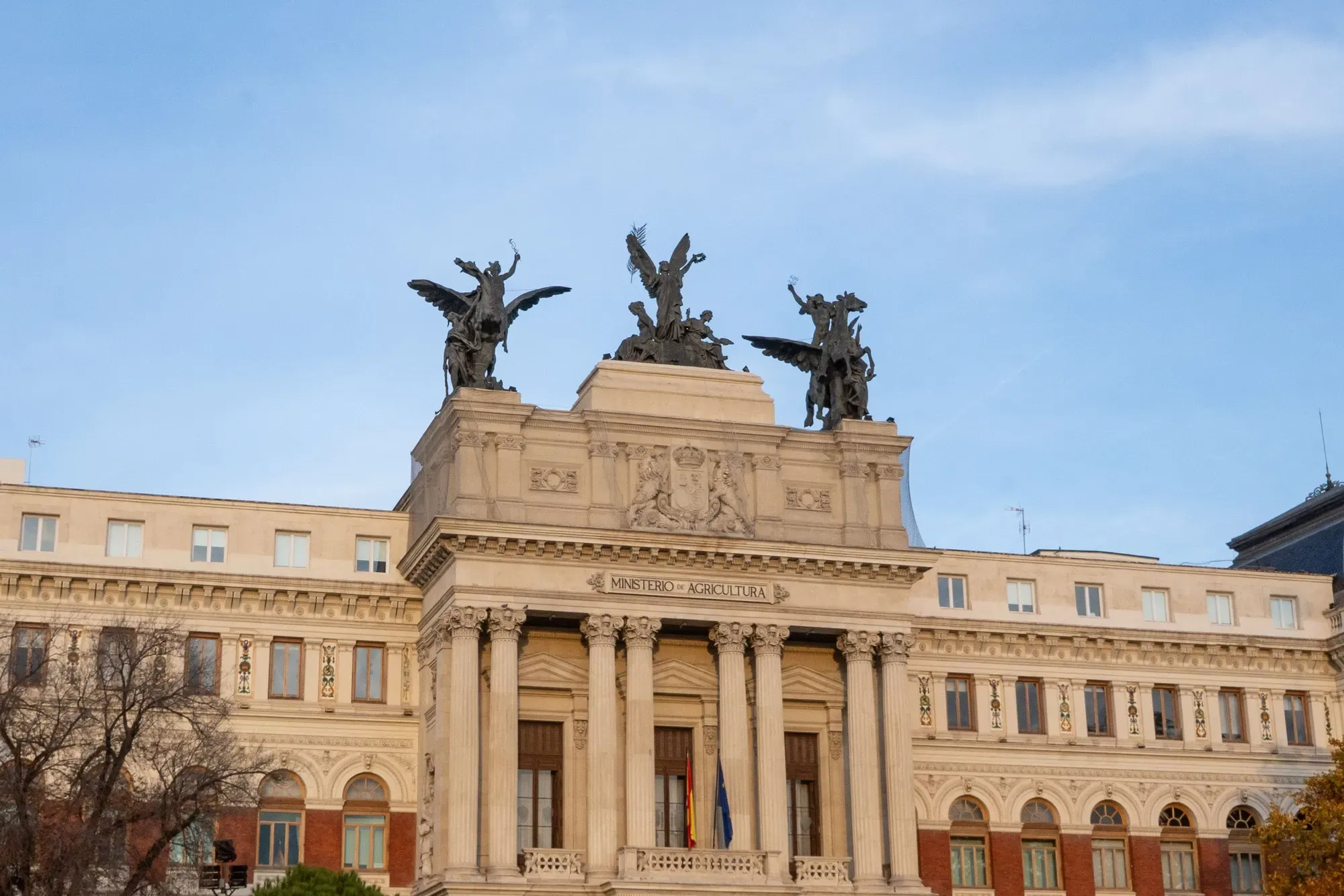 Fachada del Ministerio de Agricultura de España, en Madrid, con sus estatuas de ángeles y cielo despejado.
